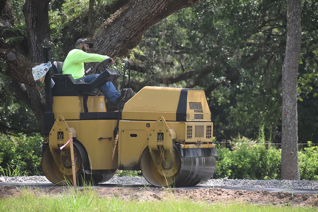 A worker paves a road that starts at the Mallaranny property&#39;s driveway and stretches toward the back of the property on April 29.