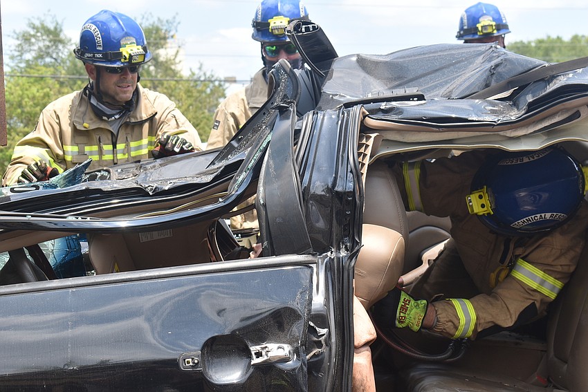 Engineers Steve Ryckman and Daniel Dunkum watch as Lt. Shawn Battick climbs his way through a battered car during a drill in which firefighters must disassemble the car to rescue the dummies in the front seat.