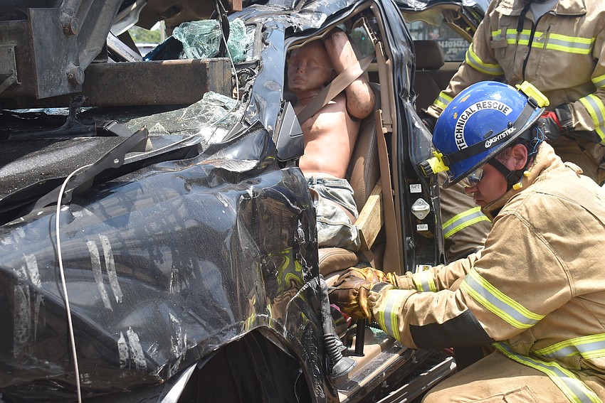 Firefighter Derek Parker uses TNT cutters as he finished prying open the doorway to the driver's side of the car.