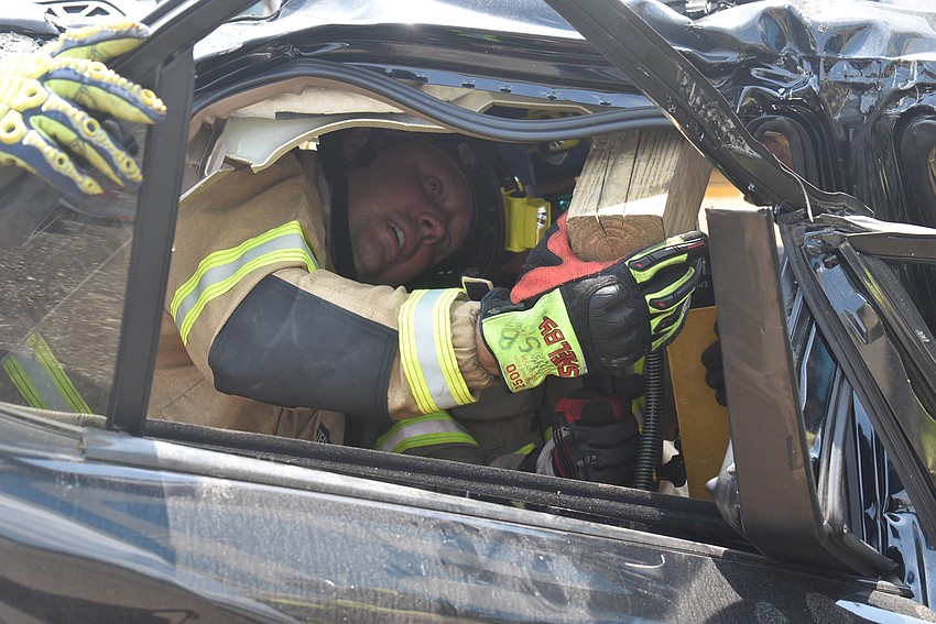 Lt. Shawn Battick and Engineer Daniel Dunkum use a piece of wood to create a larger surface area by which to reform the roof and stabilize the car, which was being crushed underneath the weight of the back of an 18-wheeler.