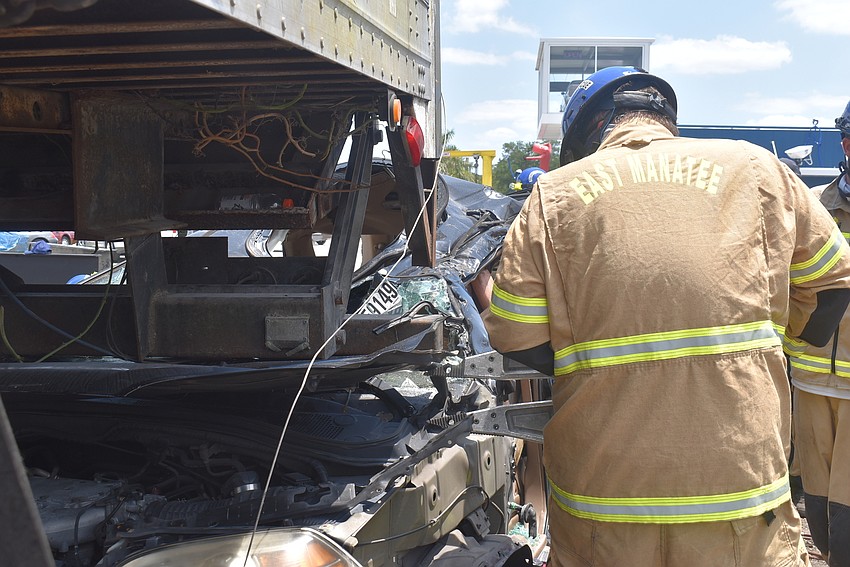 Firefighter Drew Stark pries open the hood of the car that is being crushed by the back of an 18-wheeler. The goal of the exercise was to rescue the dummies in the front seat of the car.