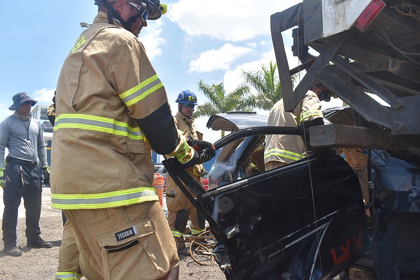 Adjunct Instructor Greg Escarra watches as Lt. Shawn Battick, Firefighter Derek Parker and Engineer Daniel Dunkum dismantle the car trapped under the back of an 18-wheeler.
