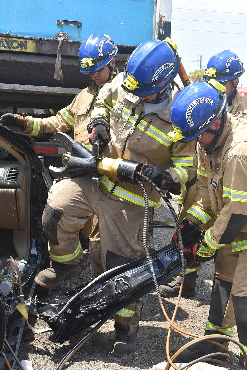 Firefighter Derek Parker, Engineer Daniel Dunkum, Lt. Shawn Battick and Engineer Steve Ryckman dismantle the door on the passenger's side of the front seat. Dunkum stomped on the door to complete the detachment.