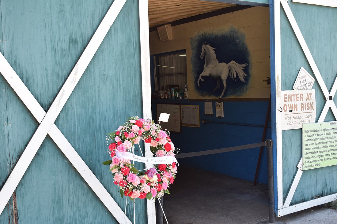 A wreath of flowers hangs at the entrance to the stable area during the Celebration of Life for Gabby Herrmann.