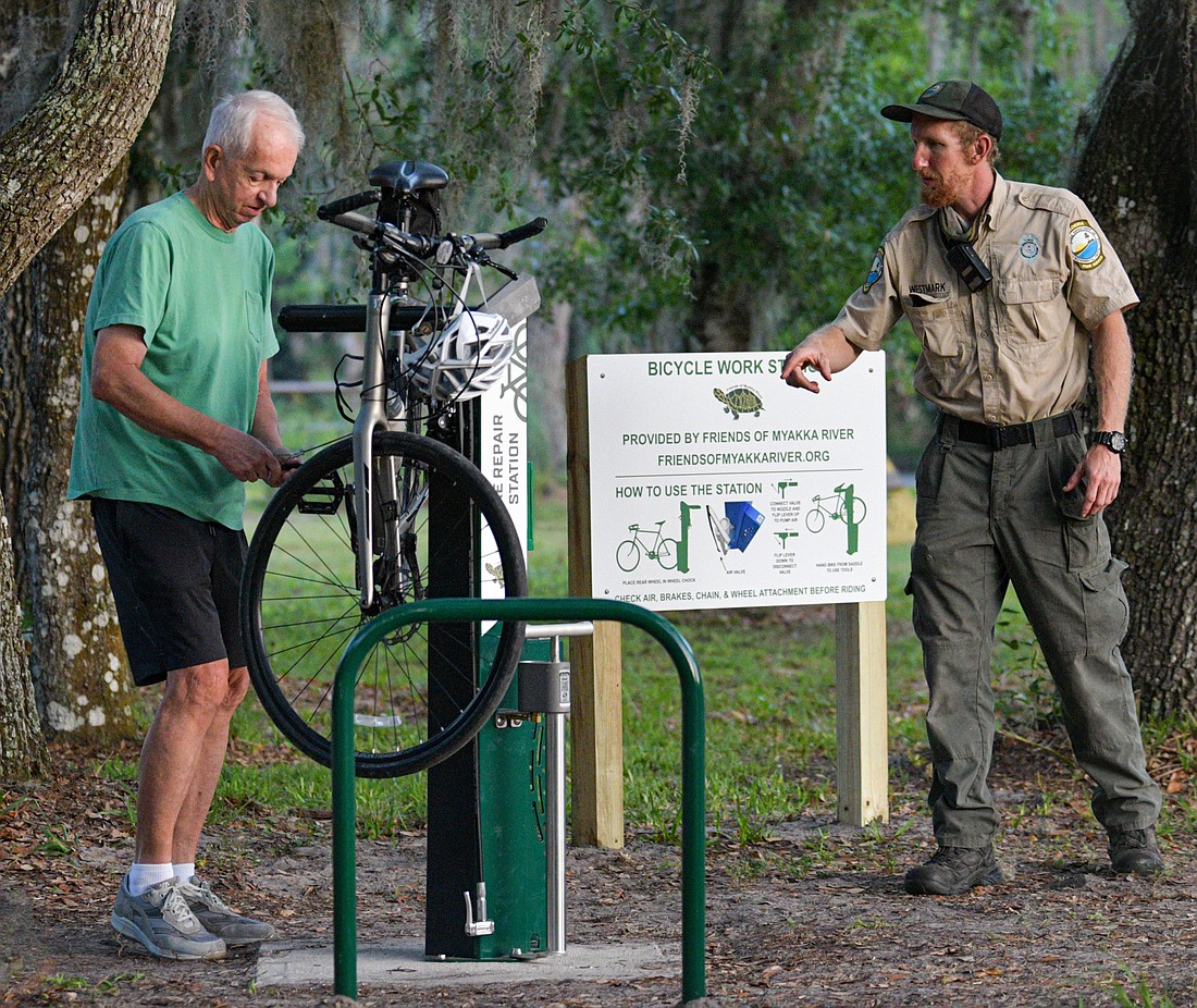 Ranger Zack Westmark helps Bill Jones of South Sarasota, a frequent biker at the park, use the new bike work station funded by Friends of Myakka River. (Miri Hardy photo)