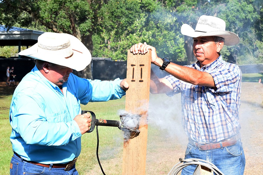 Brian Jones and Brian Broxson with Blackbeard's Ranch demonstrate how they brand their cattle. Jones says they brand the cow on its upper hip so it can easily be seen.