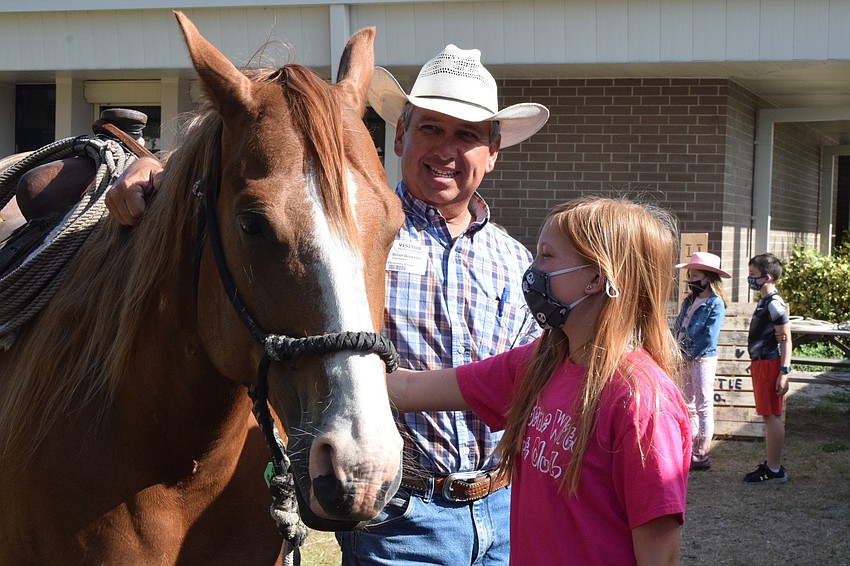 Brian Broxson with Blackbeard's Ranch holds onto Spade as Gene Witt Elementary School fourth grader Brylee Barnett pets him. 
