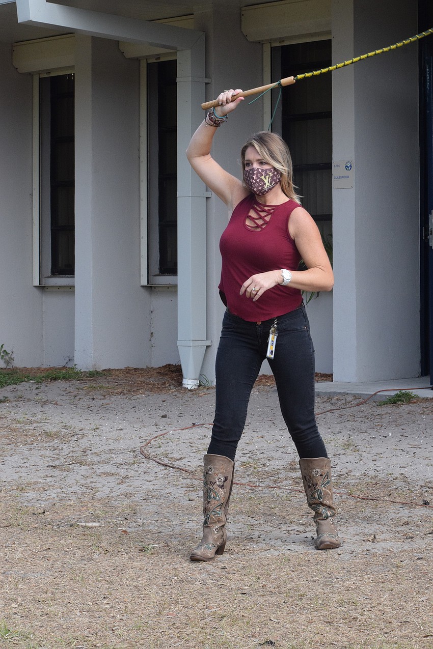 Ellie Dauphas, a fourth grader teacher at Gene Witt Elementary School, tries her hand at cracking a whip.