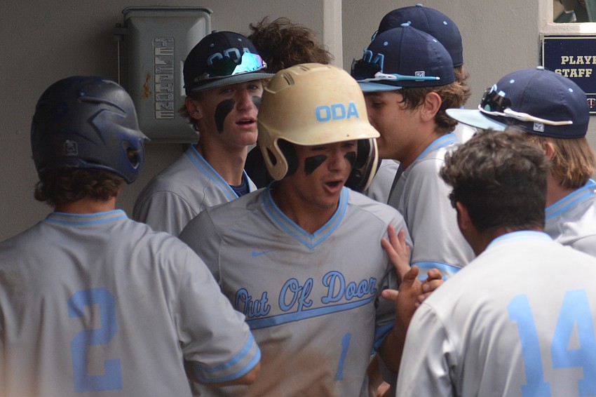 ODA senior Logan Tribble is mobbed in the dugout after scoring the game's first run on an RBI from junior Carter Dierdorf.