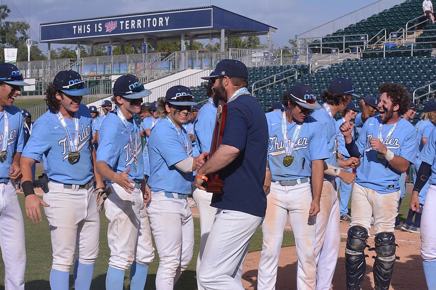 ODA Coach Mike Matthews high fives every member of the team while holding the state championship trophy.