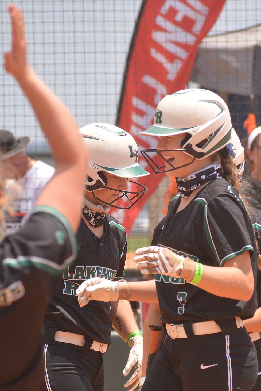 Teammates greet sophomore Cassidy McLellan at home plate after McLellan's leadoff home run.