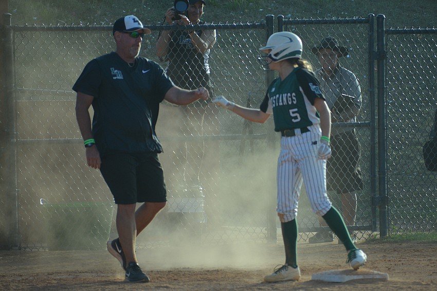 Lakewood Ranch Coach TJ Goelz fist bumps junior Ella Coiner at third base.