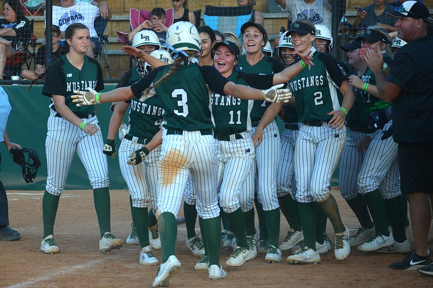 The Mustangs greet sophomore Cassidy McLellan (3) at home plate following McLellan's game-ending triple.
