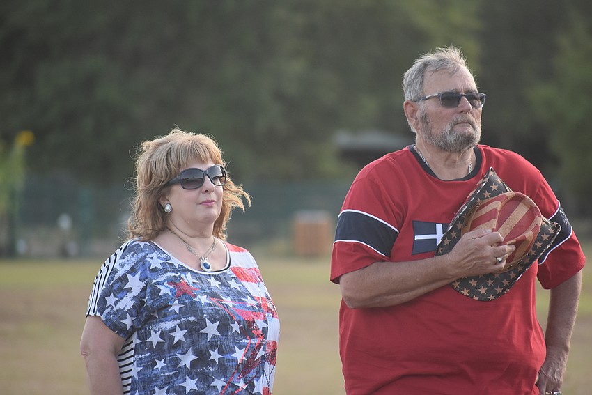 Summerfield's Julie and Wayne Seel stand at attention during the playing of God Bless America. Wayne said he came to support veterans because 