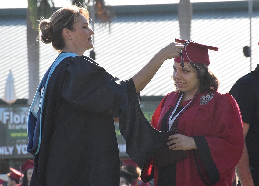 Principal Sharon Scarbrough puts Melia Butler's tassel on the left side of her cap to show she has graduated.