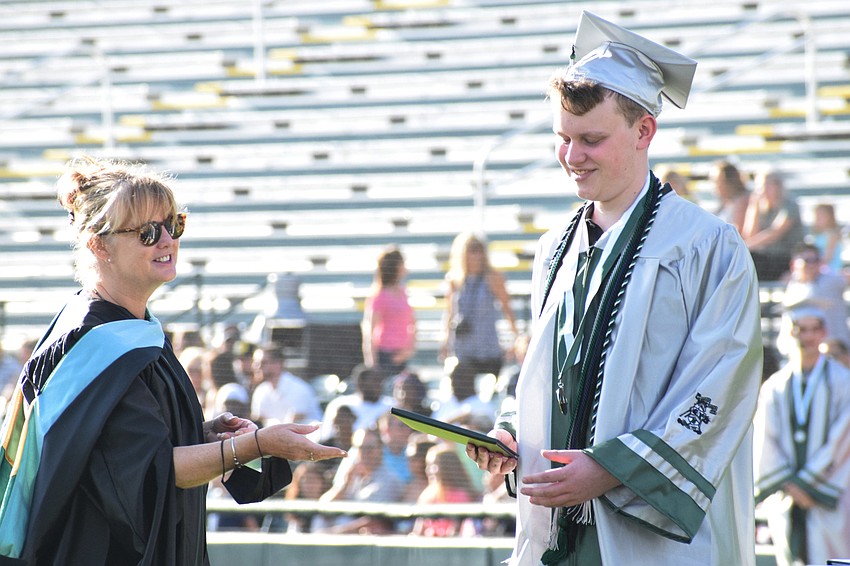 Assistant Principal Jillian Bieber presents senior Zachary Miller with his diploma.