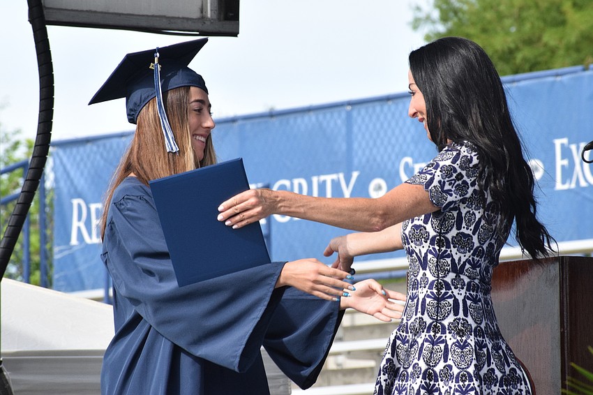 Senior Lexi Kozel hugs her mother, Ashley Kozel, who is the chair of the school's board of trustees, as she accepts her diploma.