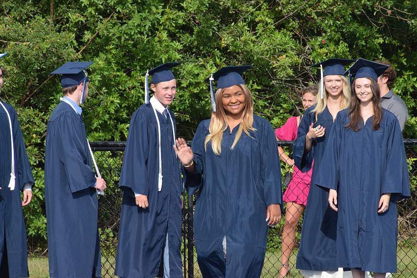 Senior Grace McCollum waves to family during the processional.
