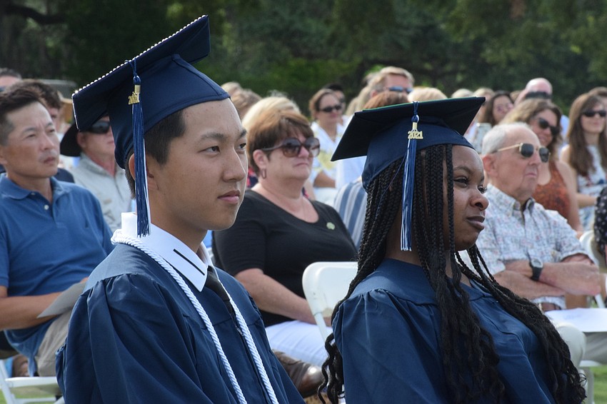 Seniors Arthur Wang and Saraiah Walkes listen as senior Reece Whatmore gives her speech as valedictorian.