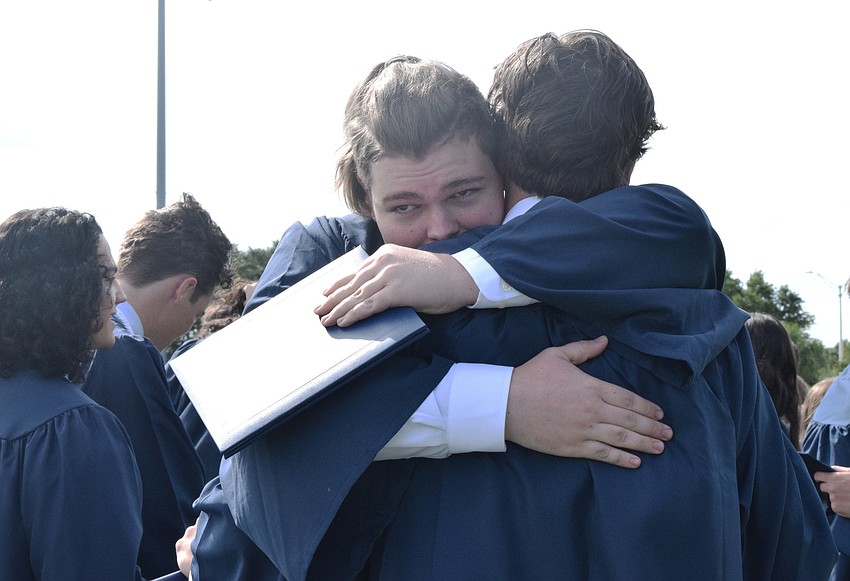 Graduate Dru Cappar hugs fellow graduate Patrick O'Keefe.