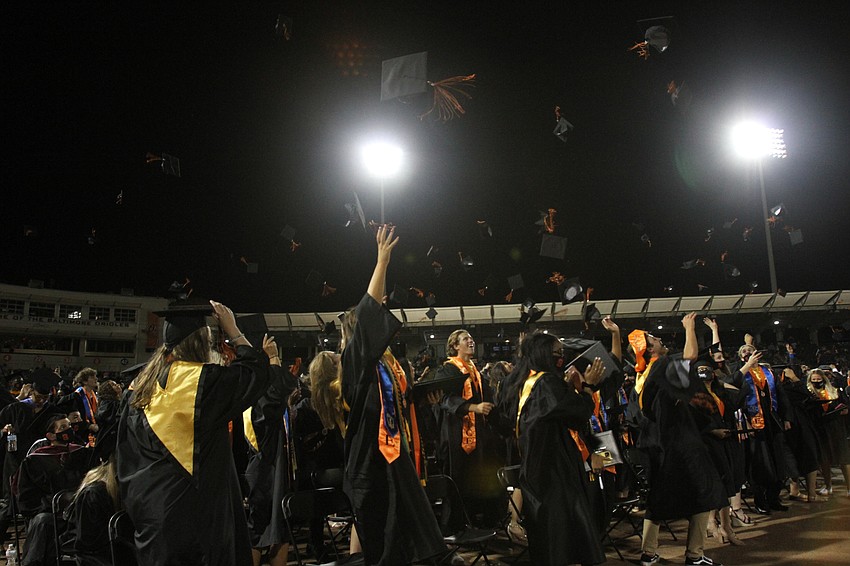 Graduates toss their caps into the air.