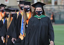 Graduates walk in two lines to their seats.
