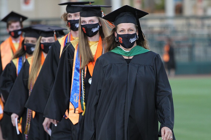 Graduates walk in two lines to their seats.