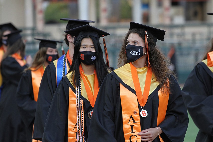 Graduates walk in two lines to their seats.