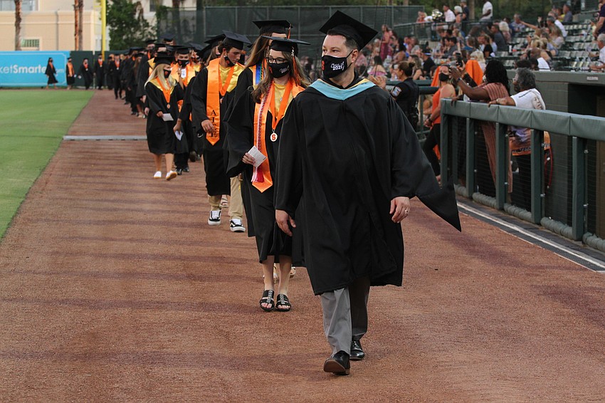 Graduates walk in two lines to their seats.