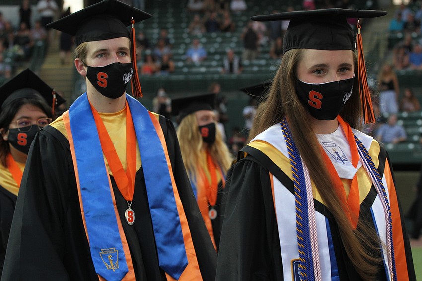 Graduates walk in two lines to their seats.