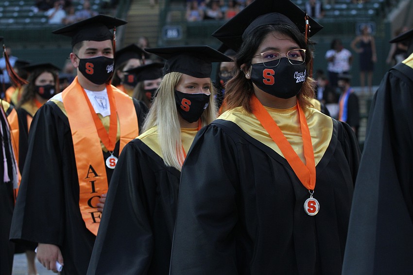 Graduates walk in two lines to their seats.