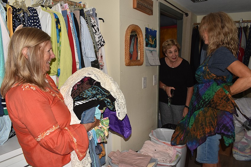 Shelly Harrison, right, tries on a dress as Virginia Luke and Karen Pashkow offer feedback.