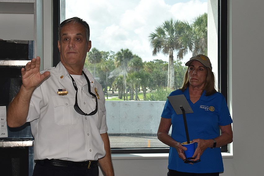 Fire chief Paul Dezzi leads a tour of the fire station while Nancy Rozance watches and holds the tree's plaque.