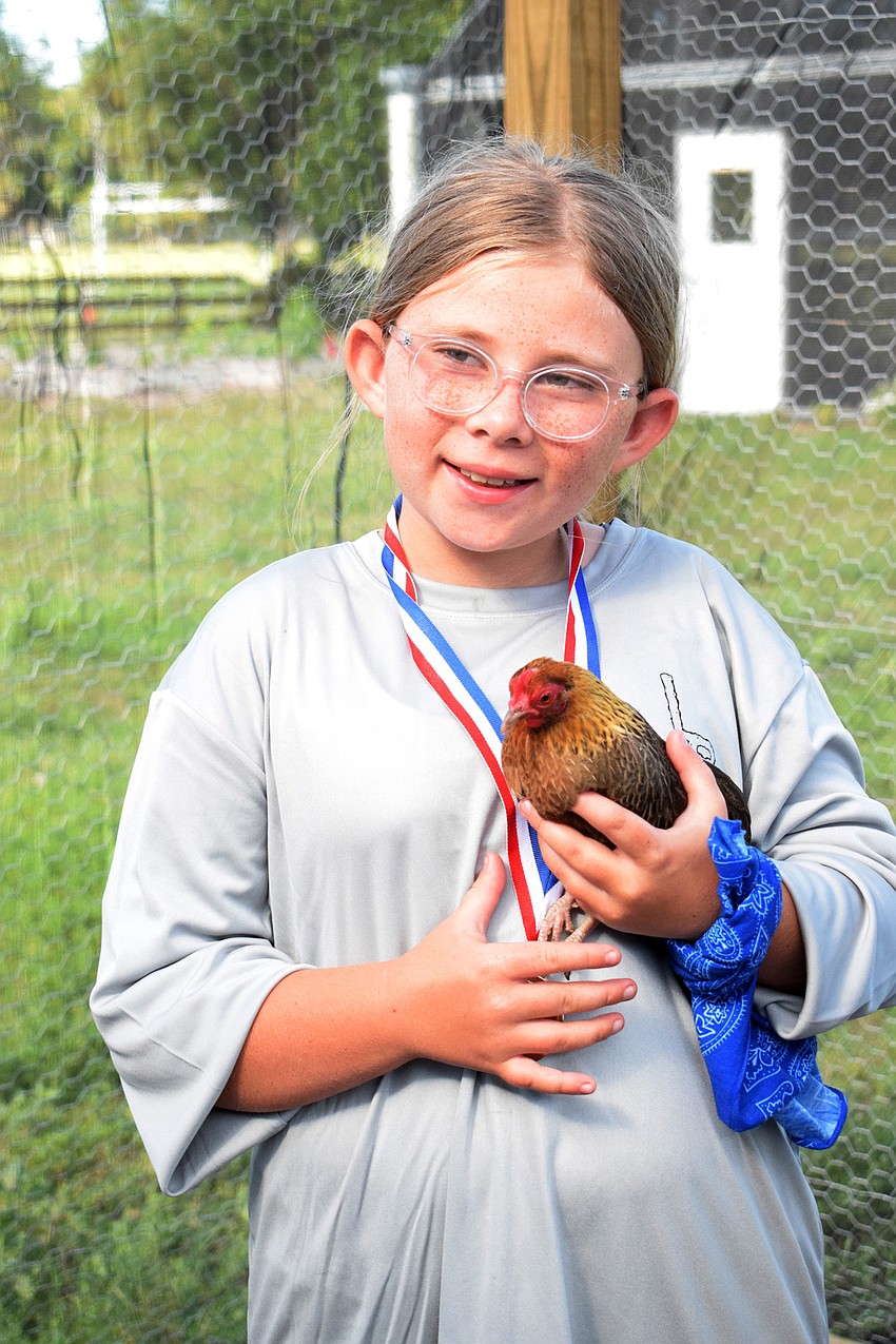 Sage Stevens, a rising fourth grader at Woodland Elementary School, holds onto a chicken.