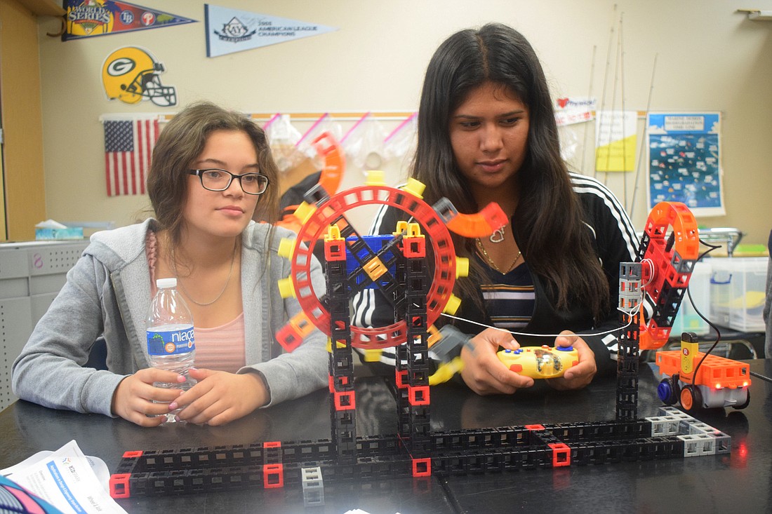 Selia Rodriguez, a rising eighth grader, and Miriam Castrejon, a rising freshman, demonstrate how their ferris wheel works. Castrejon says building the ferris wheel was more fun than she expected.