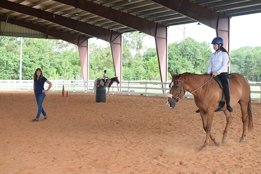 Debbie Nadeau, the barn manager at Sarasota Manatee Association for Riding Therapy, instructs Isabella Hackett, who is 11, to lower her hands on the reins while riding Cherokee.