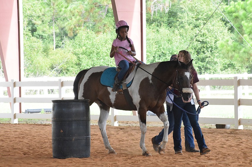 Taelyn Chapman makes her way around a barrel on Buddy Cassidy with the help of volunteer Natalie Debaets.