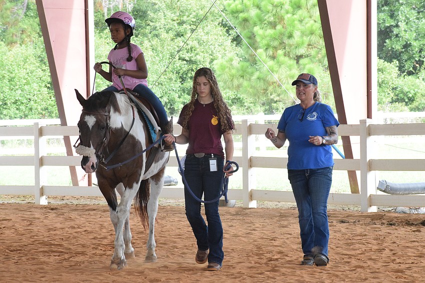Taelyn Chapman walks Buddy Cassidy with the assistance of volunteer Natalie Debaets and Sabrina Bosarge, who is a PATH instructor in training.