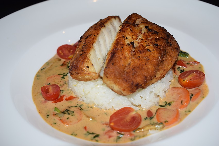 Pan-roasted Barramundi (Asian sea bass) is one of the restaurant's specialties. It is served with blistered vegetables, grape tomatoes, ginger rice and Thai Lemongrass sauce for $25.99.T