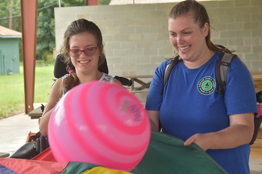 New Port Richey's Kiley Griggs, 12, and camp counselor Hannah MacDonald play a game in which people stand in a circle and move a sheet up and down in order to bounce a ball in the air and prevent it from touching the ground.