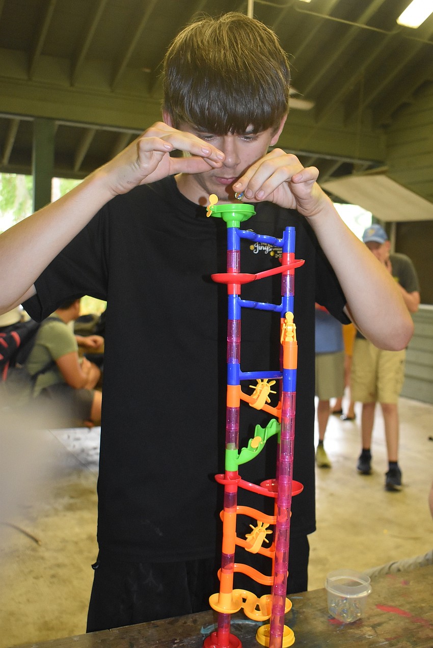 Colton Shima, 17, drops marbles down a series of tubes and slides as part of a game known as Marble Run. Shima counted 26 marbles in the set and said playing with the game was his favorite part of camp.