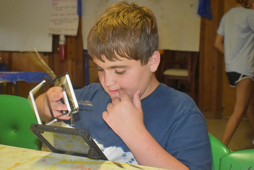 Luke Kalinowski, 12, plays with a ladder and iPad during arts and crafts time.