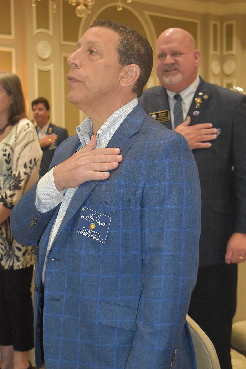 Joe Najmy and District Governor-Elect Andy Lyman stand at attention for the Pledge of Allegiance at the start of the dinner. Lyman later gave a speech about his childhood experience with illiteracy and the importance of reading.