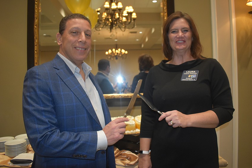 Joe Najmy and President Laura Adcock prepare to cut the cake, which was shaped like the number 20 to celebrate the club's 20-year existence.