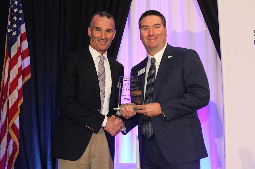 Darrin Rohr hands the Rising Star Award to Dennis Murphy with Gulfside Bank.