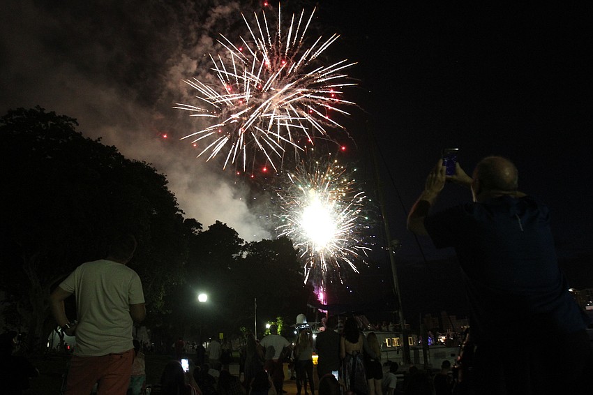 Visitors sit at Bayfront Park for the fireworks.