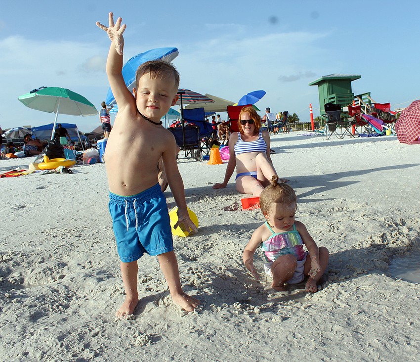 Jackson Smith throws sand while his sister Eliza Smith plays in the water.