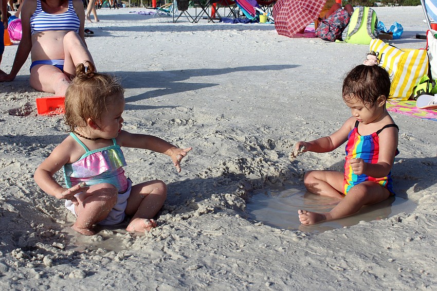 New friends Eliza Smith and Emily Ulloa play in the sand together.