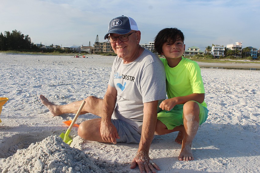 David and Nolan Brinn build a sandcastle together.