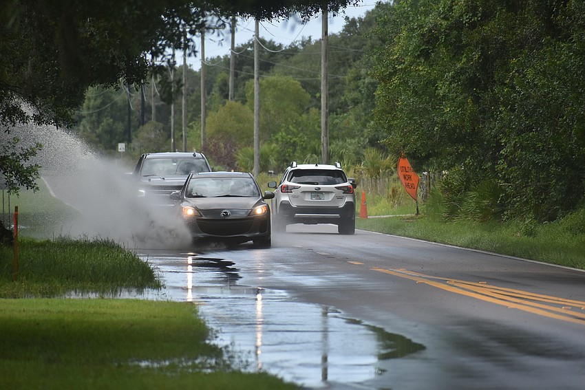 Traffic drives through standing water Wednesday morning on the side of Rye Road outside the Southern Oaks neighborhood in East County. Photo by Brendan Lavell